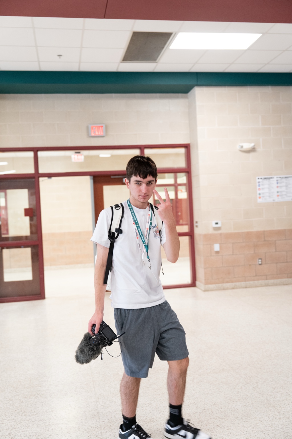 Tyson holding a camera in a school hallway